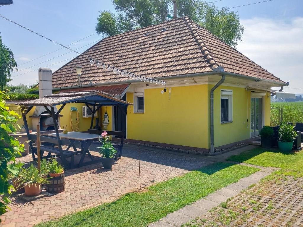 une maison jaune avec une table de pique-nique dans la cour dans l'établissement Holiday Home Lisa by Interhome, à Balatonboglár