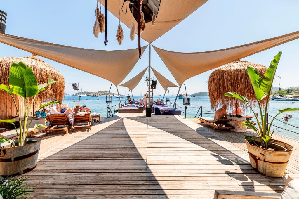 a wooden boardwalk with people sitting on chairs on the water at Elista Hotel & Spa in Golturkbuku