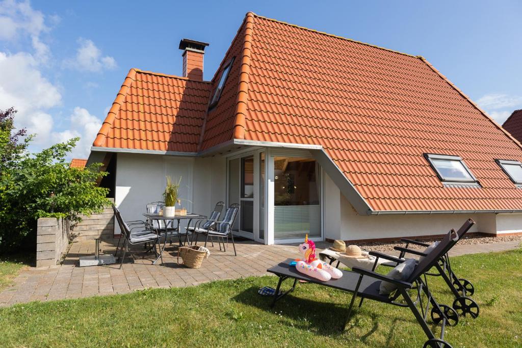 una casa con techo naranja, mesa y sillas en MP 50 - Strandvogt 3 Komfort en Dorum-Neufeld