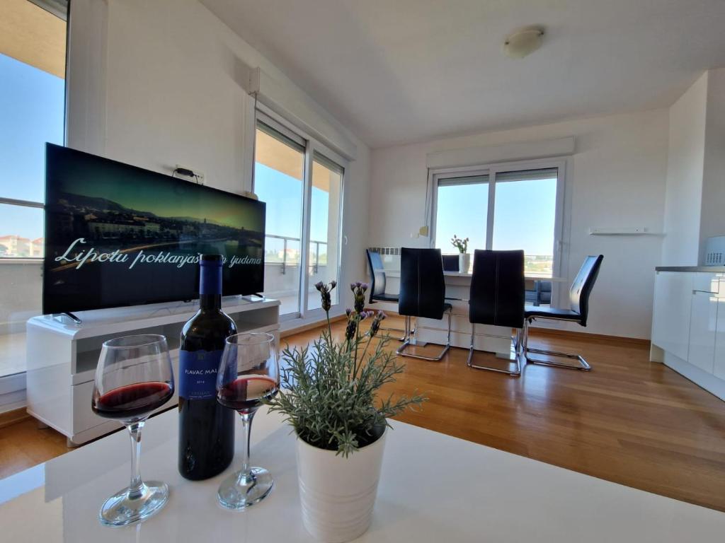 een woonkamer met wijnglazen en een flatscreen-tv bij Luxury Penthouse "MANK" with private Parking in Split