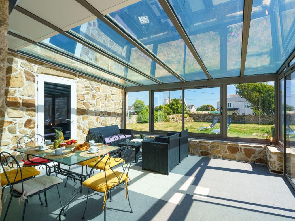 szklana oranżeria ze stołem i krzesłami w obiekcie Holiday Home L'Iroise by Interhome w mieście Plogoff