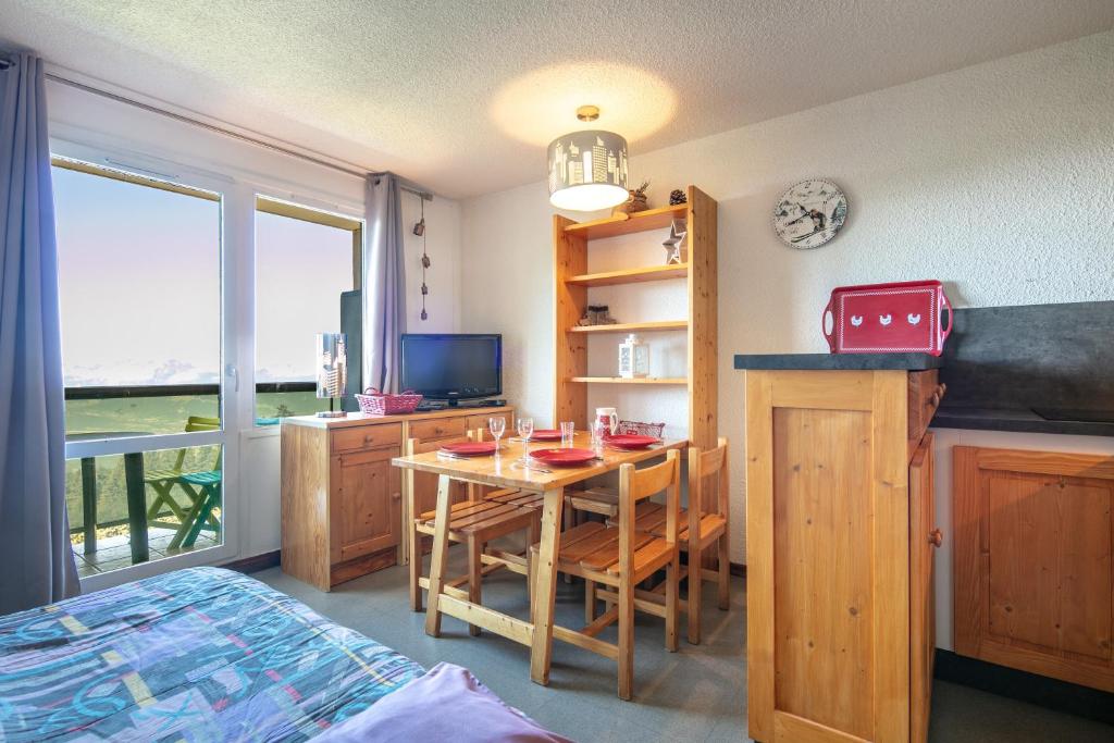 Cette chambre comprend une table, un lit et une fenêtre. dans l'établissement Le Vernon - Studio vue montagne près des pistes, à Chamrousse