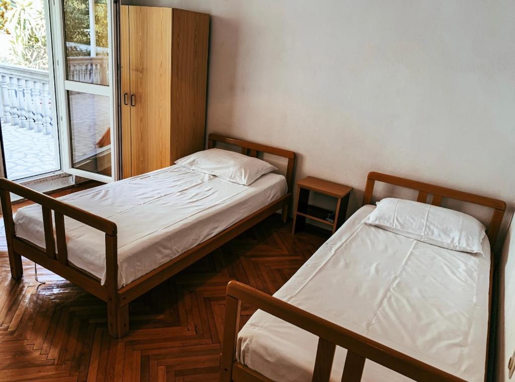 two beds in a small room with a window at Peaceful, Cosy Tivat Guesthouse in Tivat