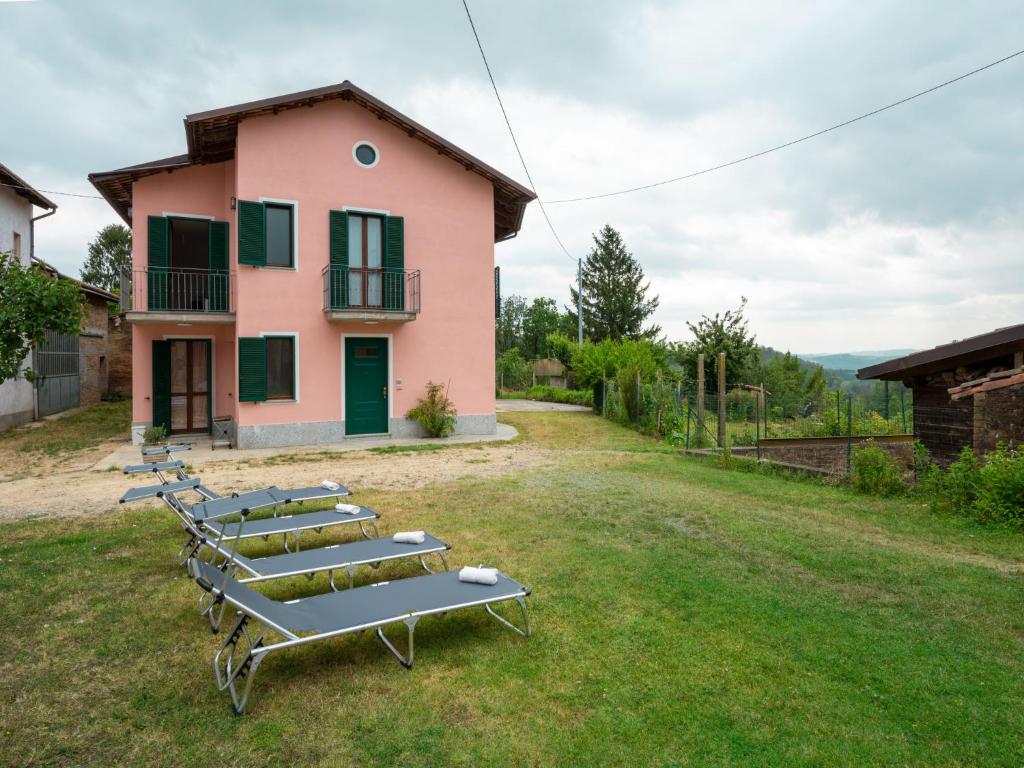 a row of lounge chairs in front of a pink house at Holiday Home Vallegra by Interhome in Cortiglione