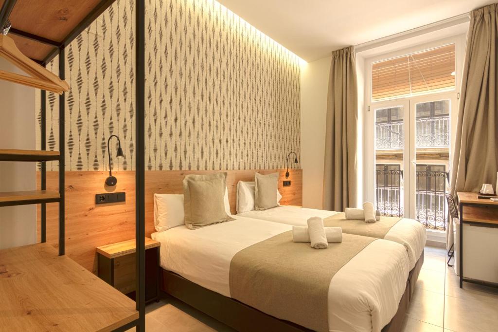 アリカンテにあるHotel La Milagrosaのベッド2台と窓が備わるホテルルームです。