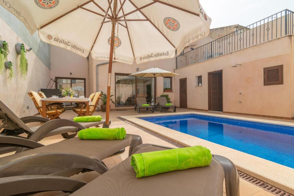een zwembad met stoelen en een parasol en een zwembad bij Villa Placeta in Sa Pobla