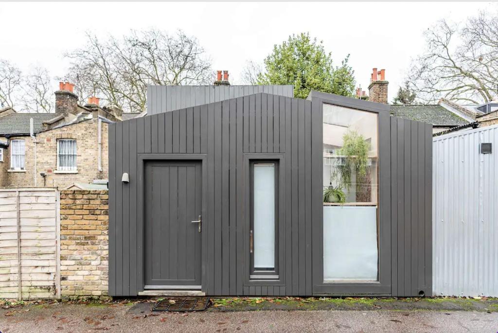 ein schwarzes Haus mit zwei Türen und einem Zaun in der Unterkunft Entire Home on Victoria Park in London