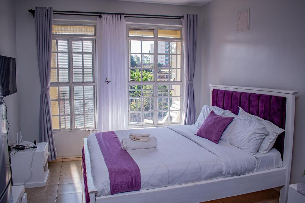 a bedroom with a large bed with a purple headboard at Belaire BnB Ruaka 3 in Ruaka