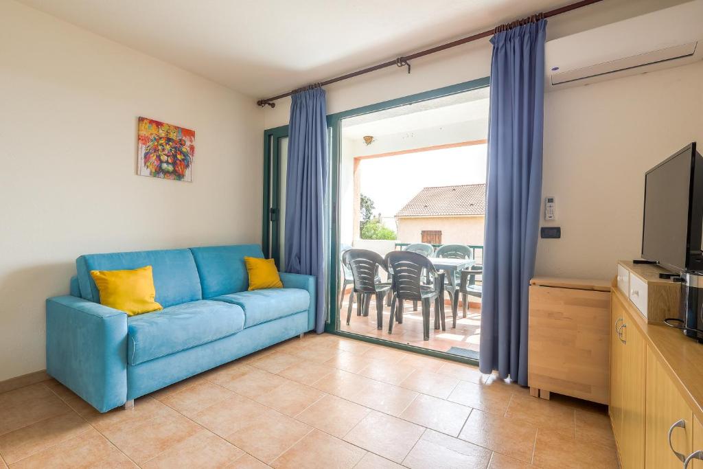 - un salon avec un canapé bleu et une porte coulissante en verre dans l'établissement La Marine de Bravone, à Linguizzetta