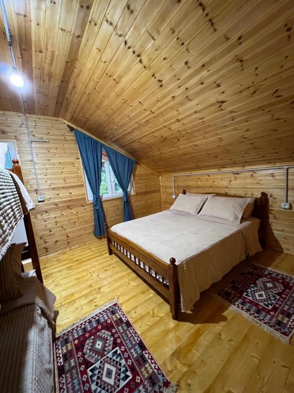 a bedroom with a bed in a wooden room at Guesthouse Zgiboza in Shkodër