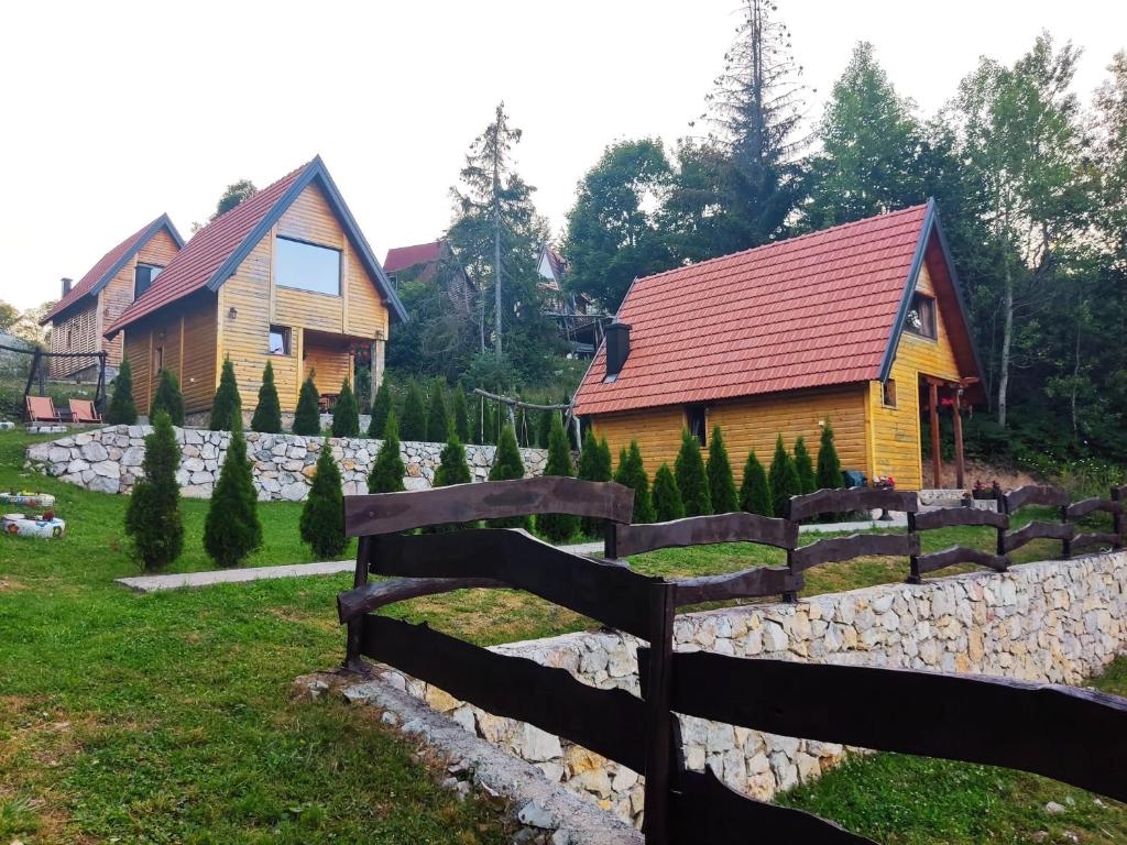 ein Holzhaus mit einem Zaun vor einem Hof in der Unterkunft Lodge Sisters in Sekulić 