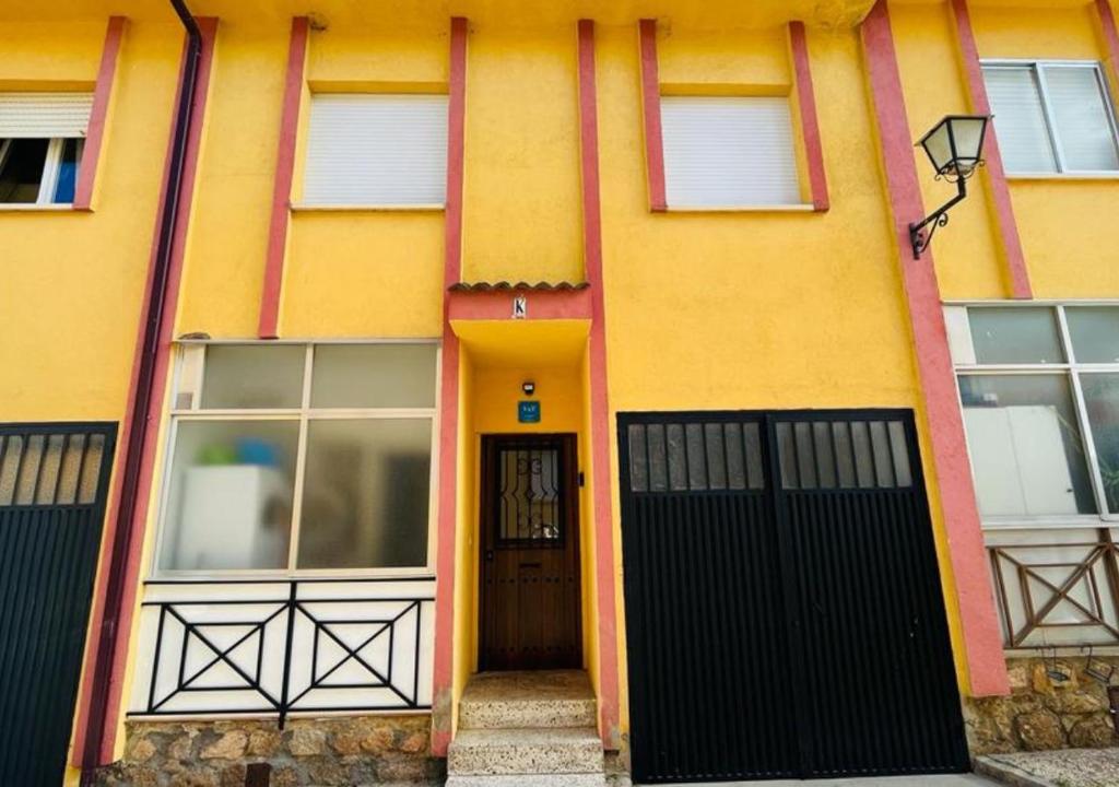 ein gelbes Haus mit schwarzen Türen und Fenstern in der Unterkunft CASA LOS PILARES in San Bartolomé de Pinares