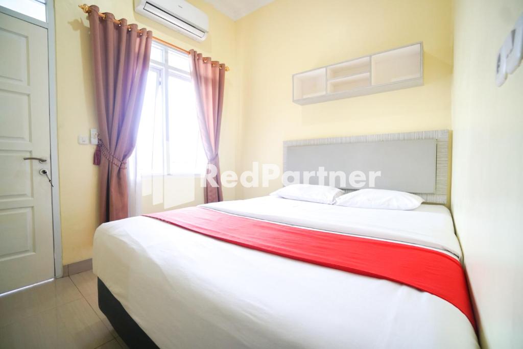 a bedroom with a large bed with a window at Indah Residence Syariah Mitra RedDoorz in Jakarta