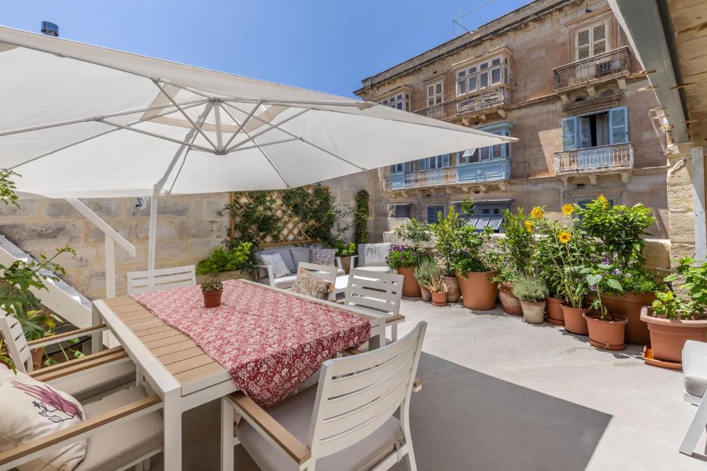 a patio with a table and umbrella and potted plants at Stunning Valletta Palazzino in Valletta