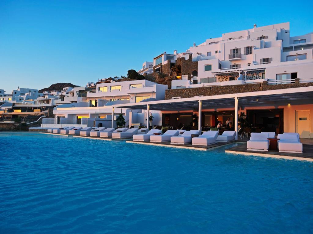 a hotel swimming pool with chairs and buildings at Kouros Hotel & Suites in Mikonos