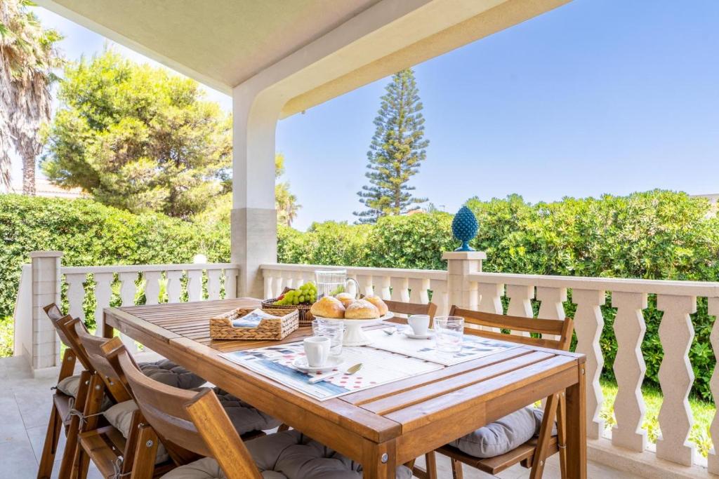 a wooden table and chairs on a porch with a view at Villa delle Lantane San Lorenzo Marzamemi in San Lorenzo