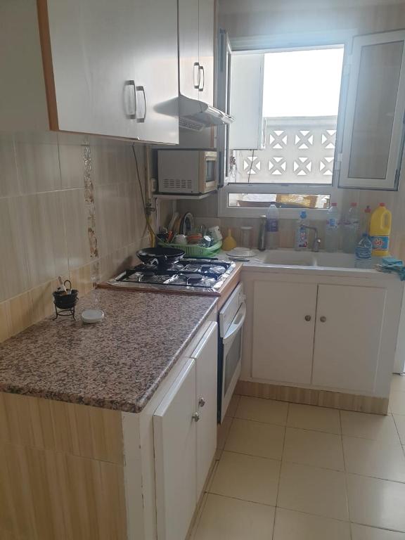 eine Küche mit weißen Schränken und einer Arbeitsplatte in der Unterkunft Appartement s+2 au plein coeur de sousse in Sousse