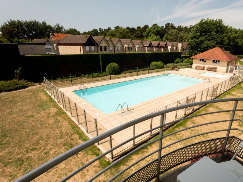ein Schwimmbad mit einem Zaun um ihn herum in der Unterkunft Apartment Green Garden-8 by Interhome in De Haan