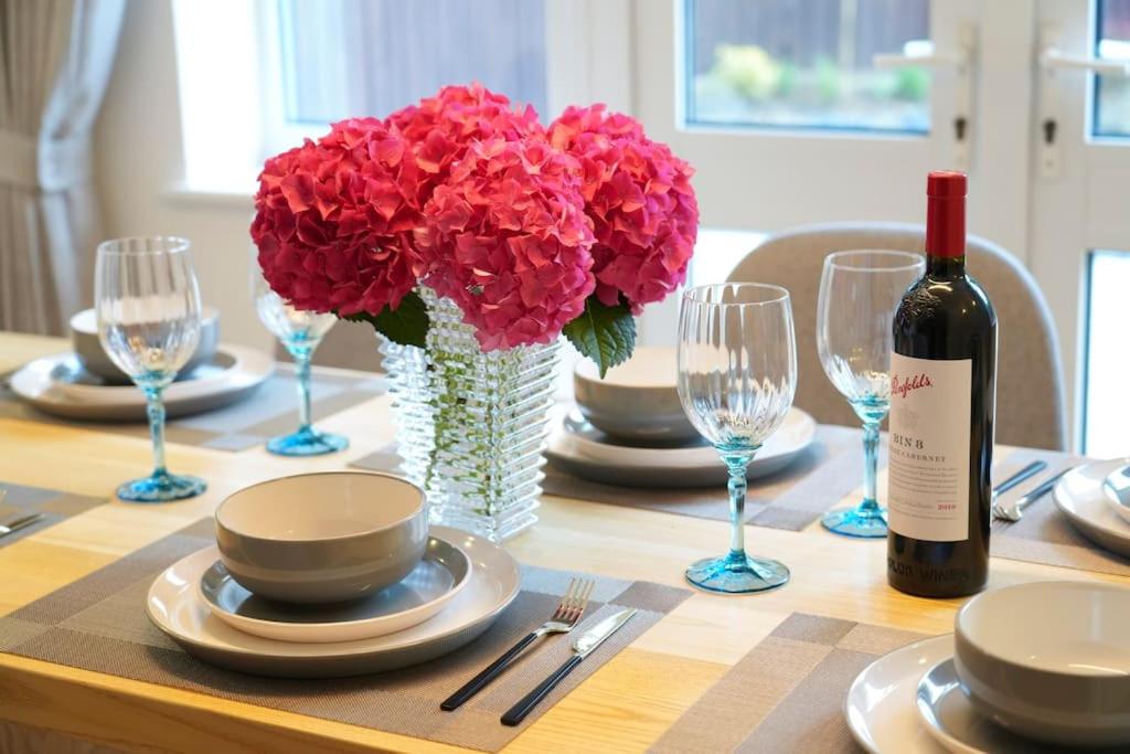 a table with a bottle of wine and a vase of flowers at Tranquil Retreat in Bicester in Bucknell