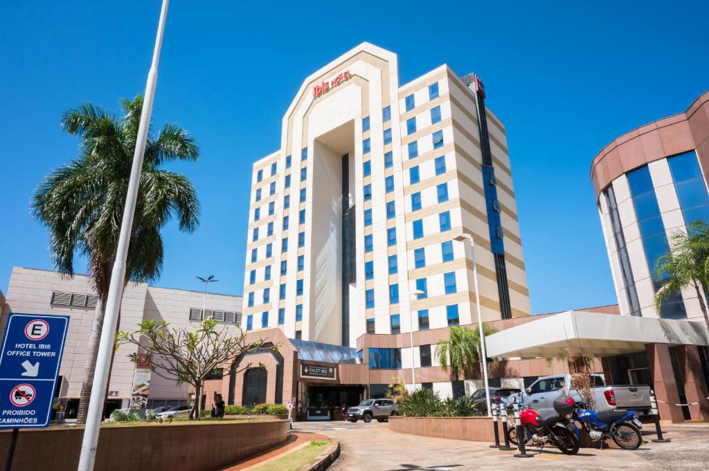 um grande edifício branco com palmeiras em frente em ibis Ribeirao Preto Shopping em Ribeirão Preto