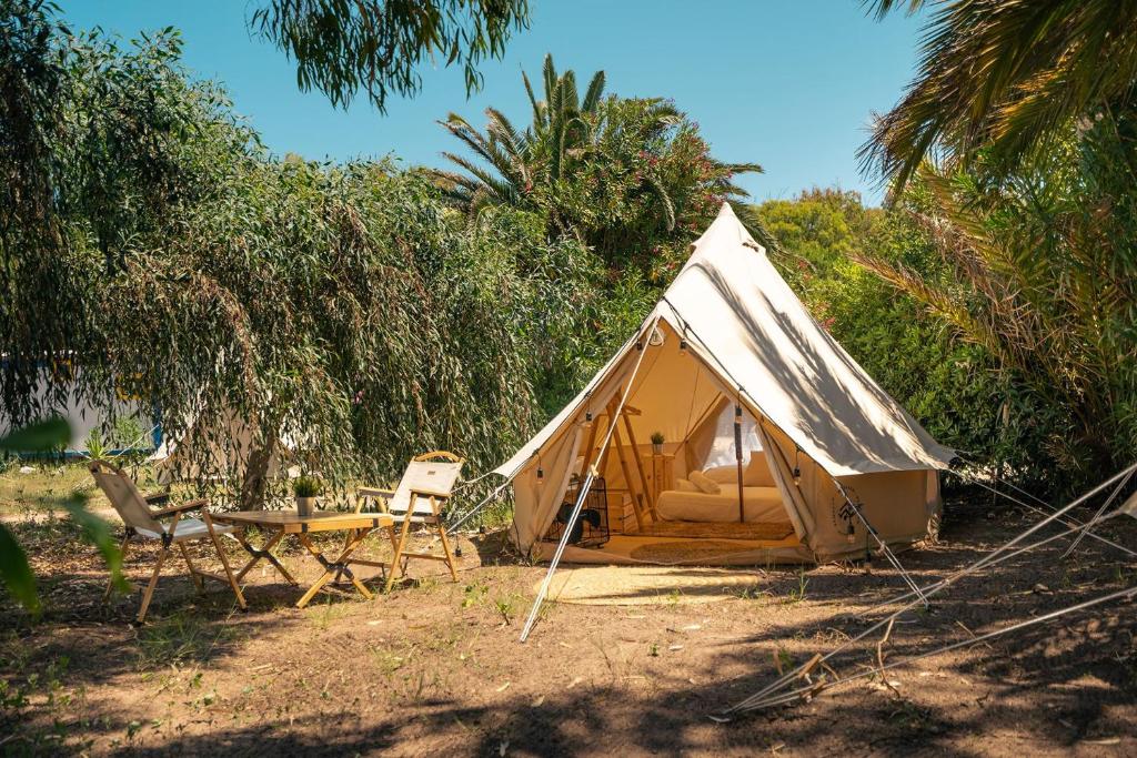 瓦雷多利亞的住宿－Kampaoh Valledoria，黄色帐篷,配有桌子和椅子