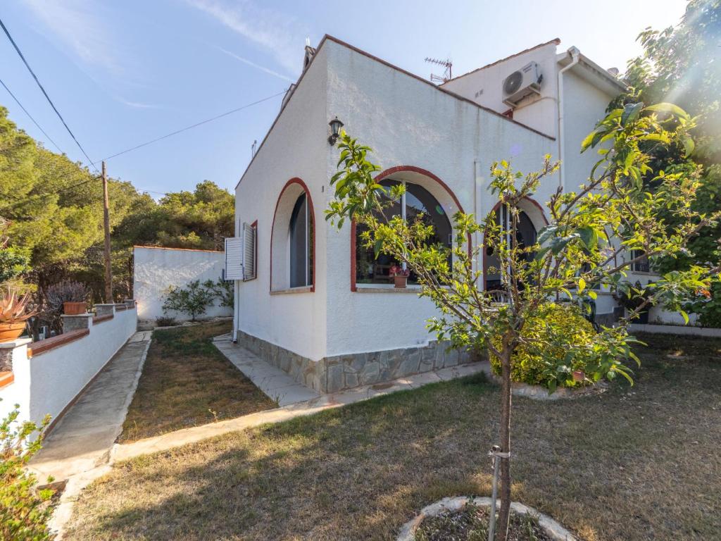 ein kleines weißes Haus mit einem Baum im Hof in der Unterkunft Holiday Home Llimona by Interhome in Creixell