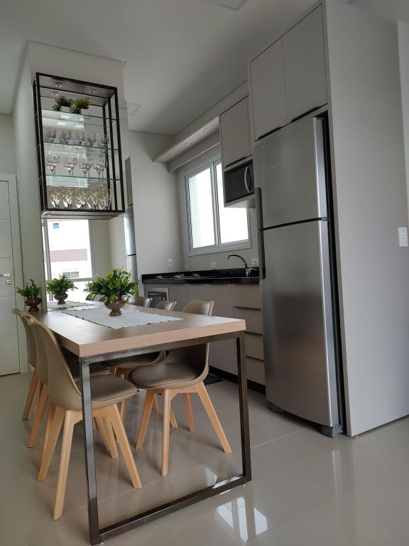 a kitchen with a wooden table and a refrigerator at Praia de Palmas - Lindo Apartamento in Governador Celso Ramos