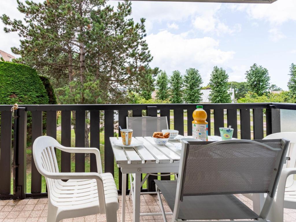 une table blanche et des chaises sur une terrasse dans l'établissement Apartment Les Portes de la Mer-11 by Interhome, à Villers-sur-Mer