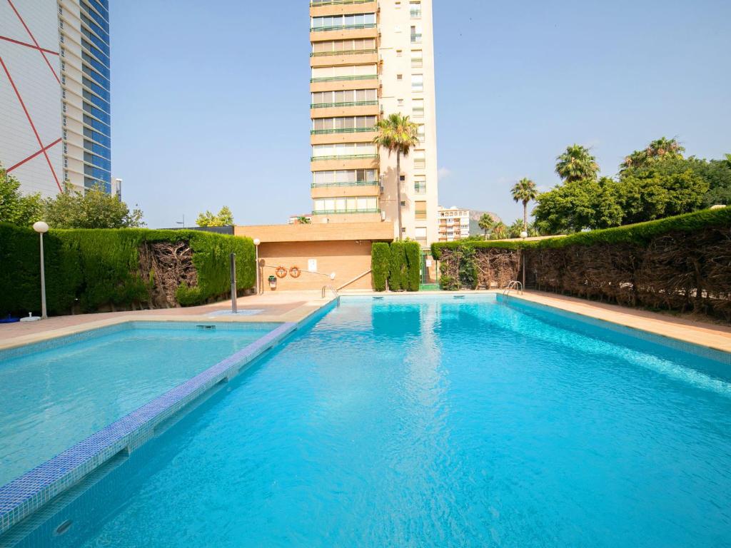 a large blue swimming pool with a tall building at Apartment Etxezuri by Interhome in Calpe