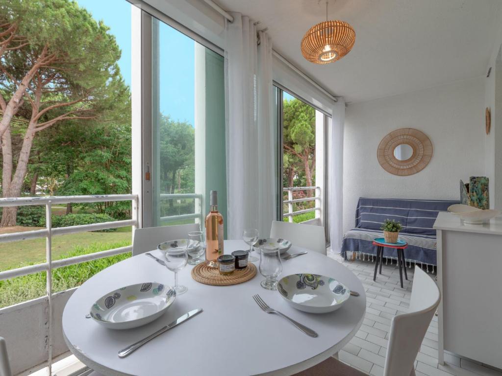 una mesa blanca y sillas en una habitación con ventanas en Apartment Les Jardins du Couchant by Interhome en La Grande-Motte