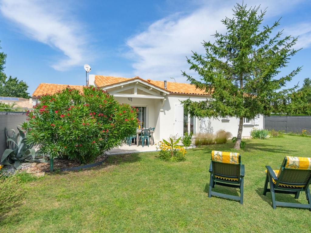 een tuin met twee stoelen en een huis bij Holiday Home Villa Margarin by Interhome in Les Mathes