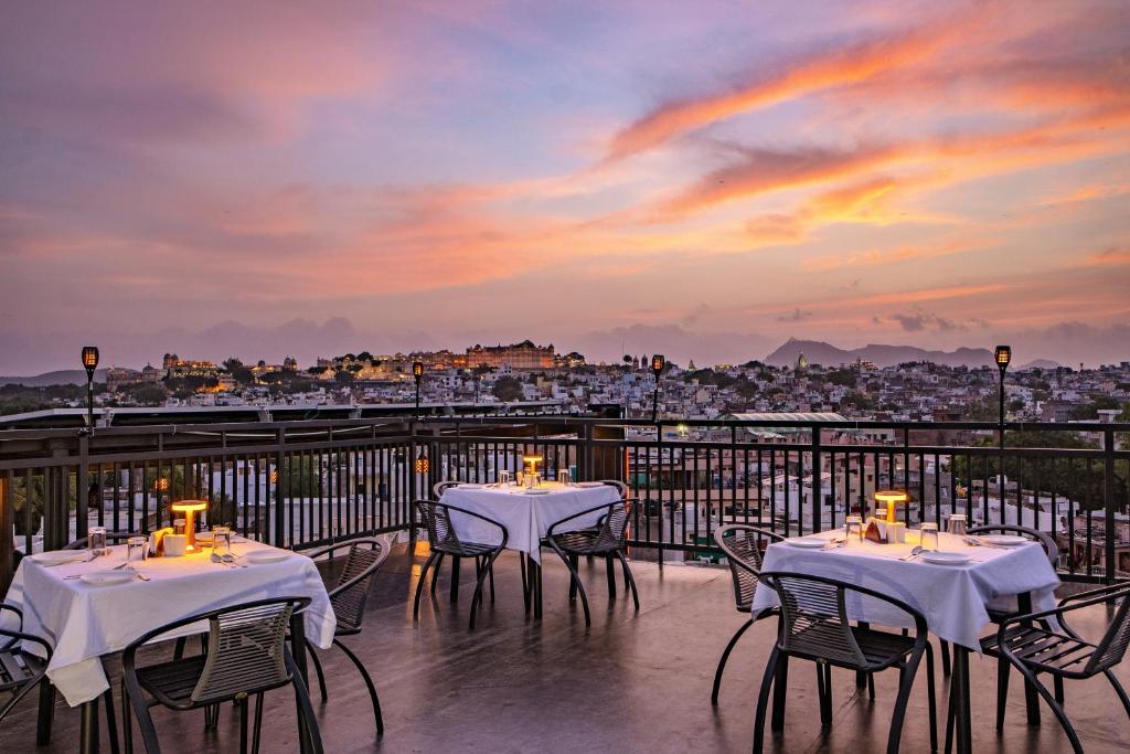 a balcony with tables and chairs with a view of a city at THE MANGAL VIEW RESIDENCY - A Luxury Boutique Business Hotel in Udaipur