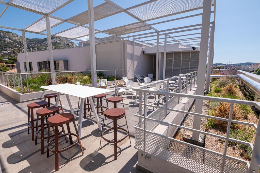 a balcony with tables and stools on a building at Hostel Le Hüb Toulon in Toulon