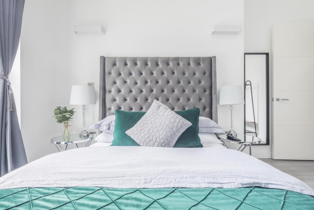 a bedroom with a large bed with green pillows at Elegant apartment in Milton Keynes