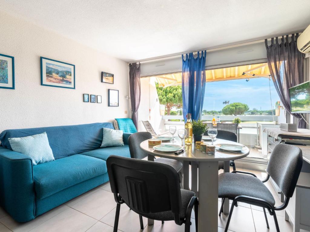 un salon avec un canapé bleu, une table et des chaises dans l'établissement Apartment Isle Catherine-4 by Interhome, au Grau-du-Roi