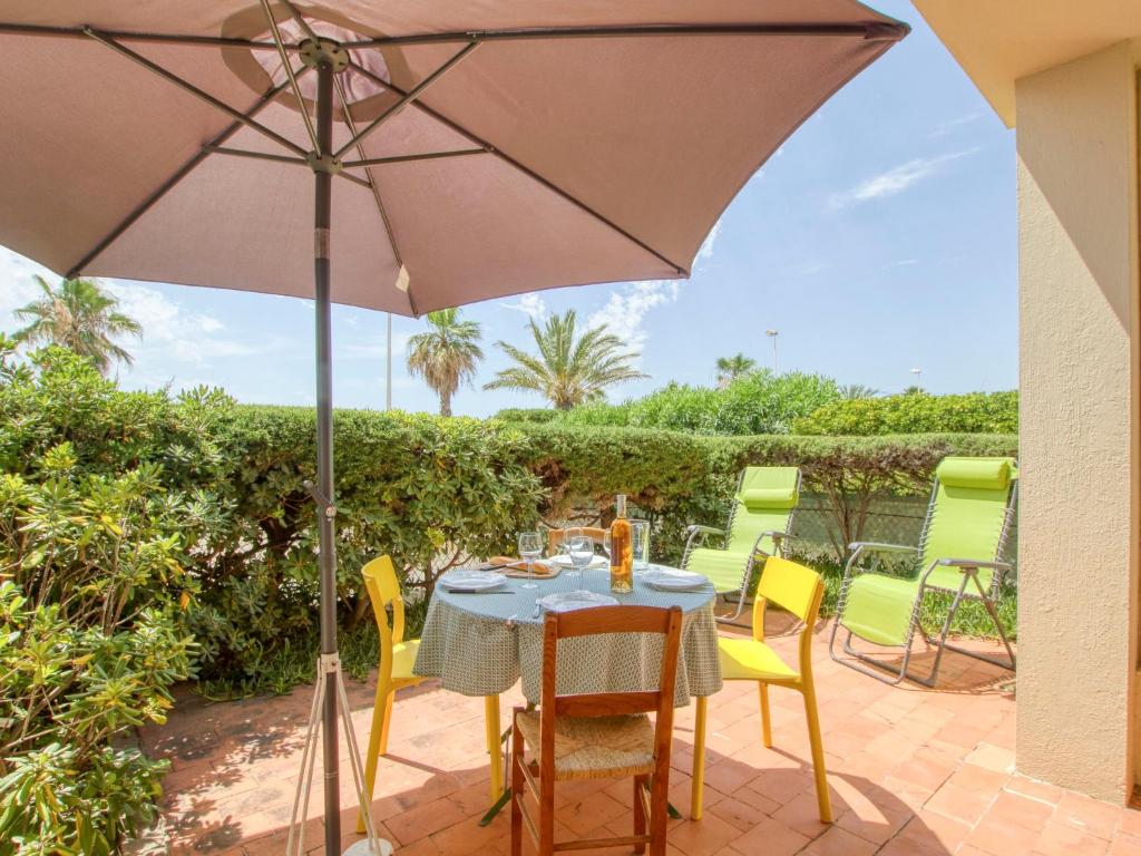 - une table et des chaises sous un parasol sur la terrasse dans l'établissement Apartment Les Vagues by Interhome, à Saint-Cyr-sur-Mer