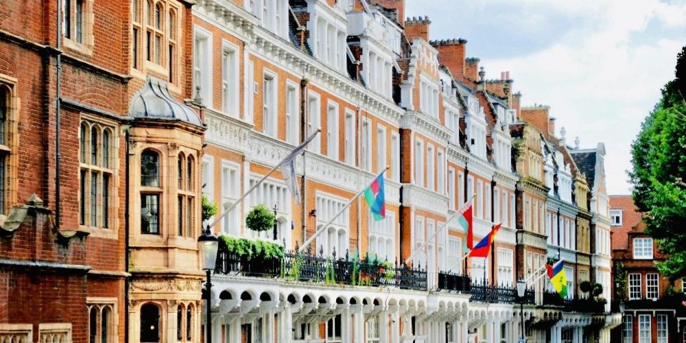 uma fila de edifícios com bandeiras à sua frente em 2 Bedroom flat in diplomatic enclave in Kensington em Londres