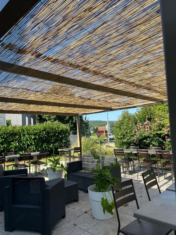 a patio with tables and chairs under a wooden umbrella at Hôtel Campanile Cahors in Cahors