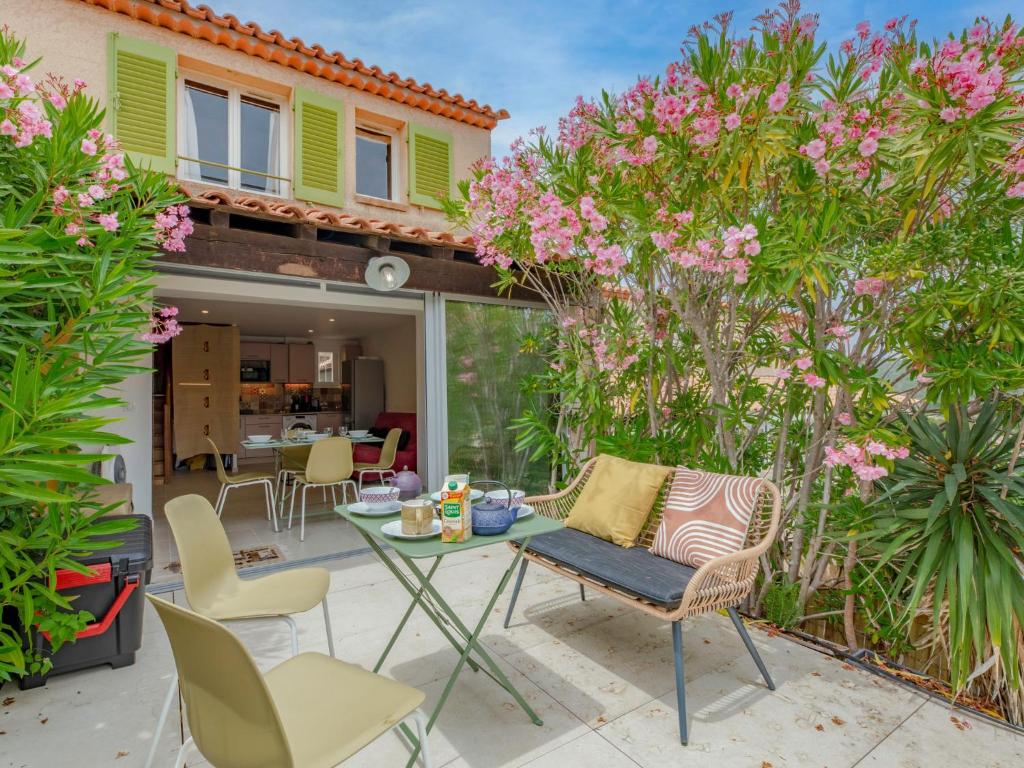 サント・マキシムにあるHoliday Home Les Bastides de Guerrevieille-7 by Interhomeのピンクの花が咲くパティオ(テーブル、椅子付)