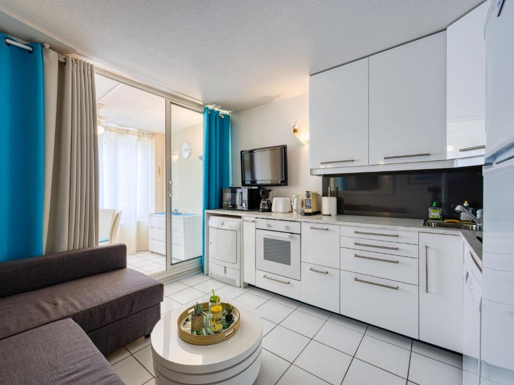 une cuisine avec des armoires blanches et un salon dans l'établissement Apartment La Palme d'Or-18 by Interhome, au Cap d'Agde