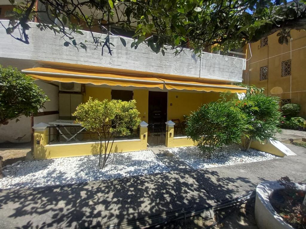 un bâtiment jaune avec une table et des chaises devant lui dans l'établissement Angela's Cute Apartment (A/C, WiFi, Little Garden), à Análipsis