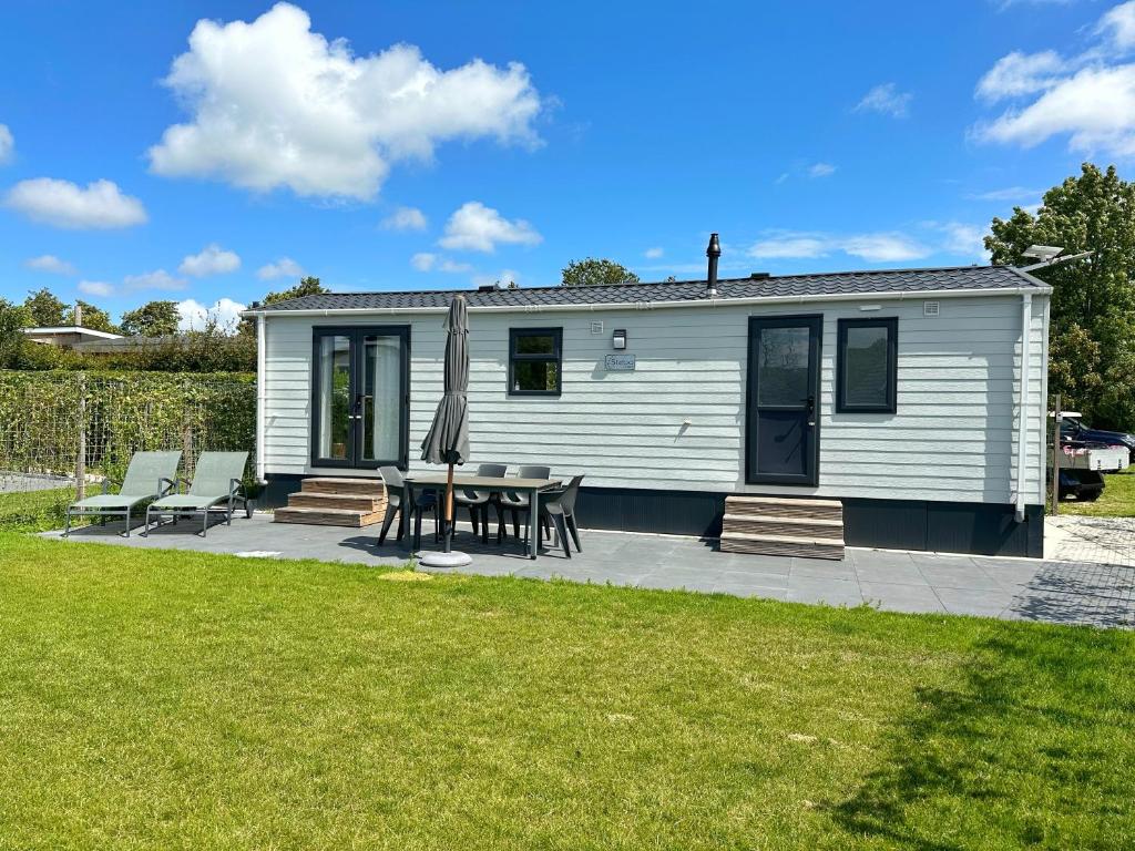 a small white caravan with a table and chairs at Chalet 579 op Recreatiepark De Wielen in Sint Maarten