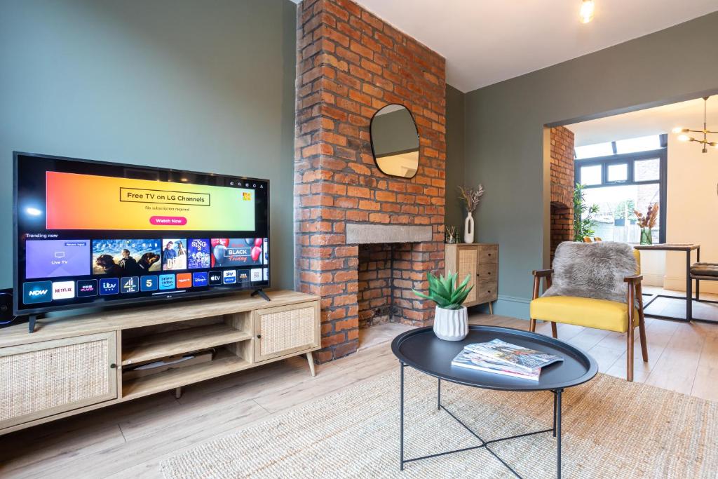 ein Wohnzimmer mit einem TV und einer Ziegelwand in der Unterkunft Stunning Scandi Abode in Manchester Parking in Manchester