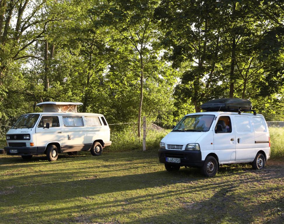 two white vans parked next to each other in a field at einfachlosmachen-BulliBus 