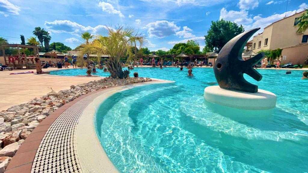 塞里尼昂的住宿－Mobil Home 2CH Bien Equipé Valras-Plage，度假村的游泳池,设有海豚喷泉