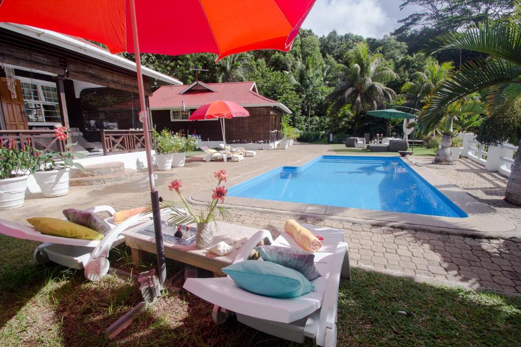 a pool with chairs and an umbrella next to a house at Kokogrove Chalets in Anse Royale