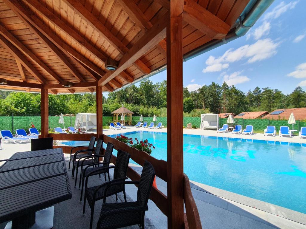 una piscina con sillas, una mesa y una piscina en Feriendorf Fuchsberg, en Schirgiswalde