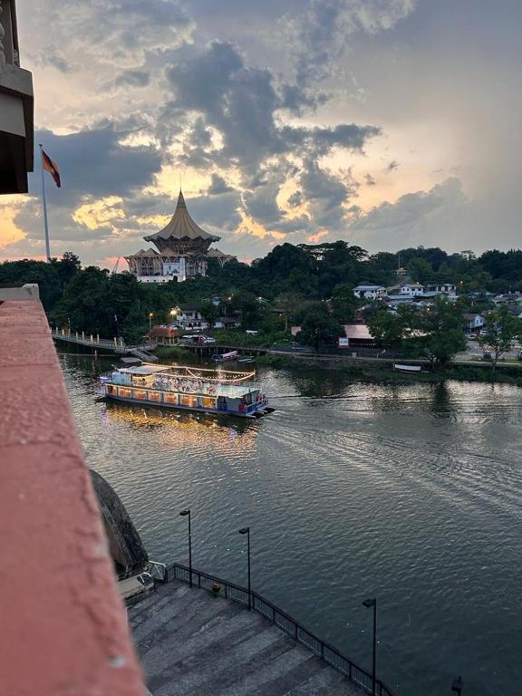 a boat on a river with a building in the background at Level 12 Riverbank suites 2BR RiverView in Kuching