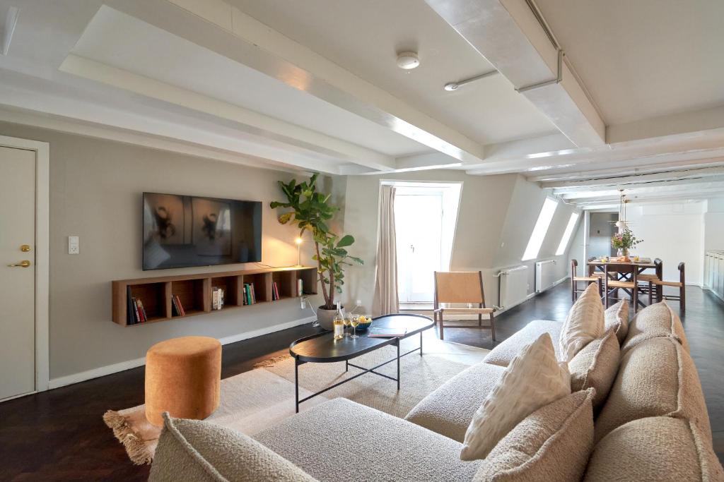 uma sala de estar com um sofá e uma televisão em LUXURY Penthouse · Private Balcony · Heart of Copenhagen em Copenhague