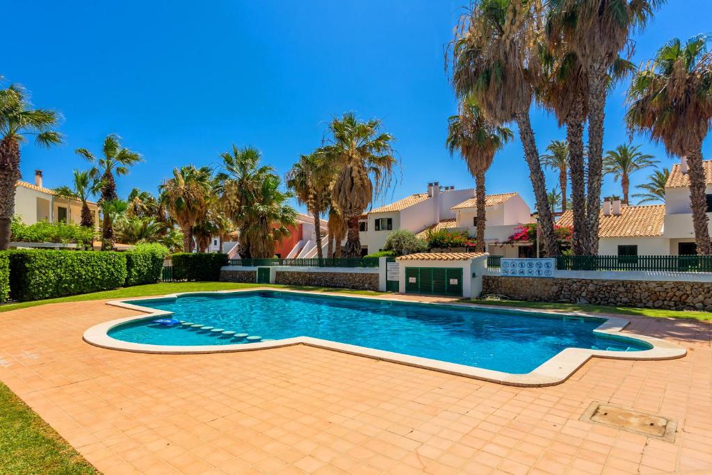 a swimming pool in a yard with palm trees at Aloes in Sa Caleta